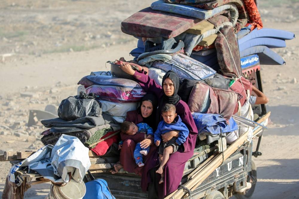 Palestinian women holding their children ride on the back of a truck as people make their way to Gaza City through the so-called "Netzarim corridor" from Nuseirat in the central Gaza Strip on October 11, 2025. Israel declared a ceasefire in Gaza and began to pull back its forces on October 10, as tens of thousands of exhausted Palestinians made their way back to their devastated homes. (AFP)