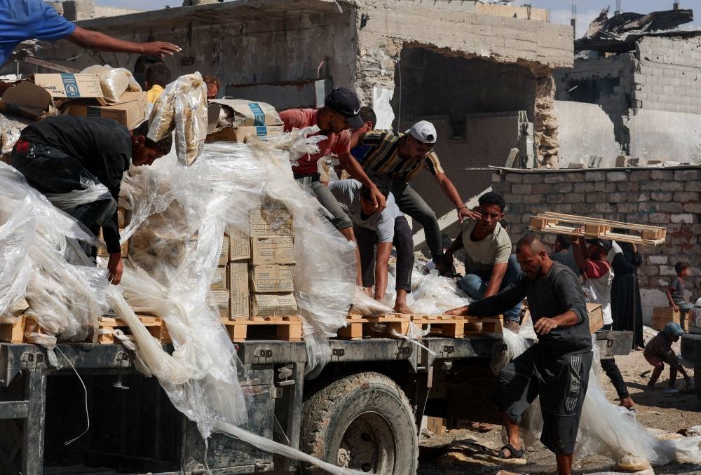 Palestinians collect aid supplies from a truck that entered Gaza, amid a ceasefire between Israel and Hamas, in Khan Younis, in the southern Gaza Strip, on Saturday. REUTERS