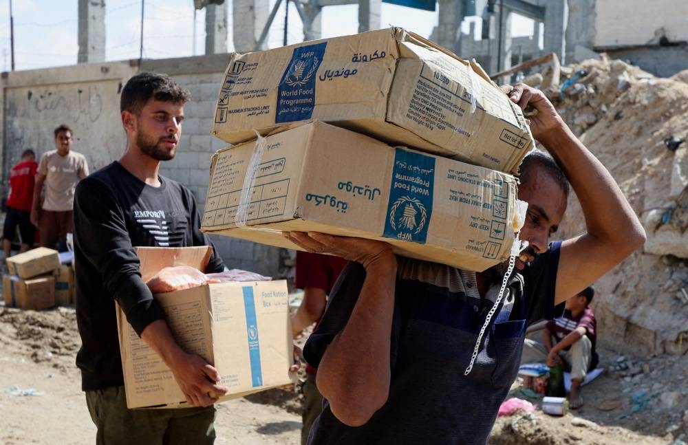 Palestinians carry aid supplies that entered Gaza, amid a ceasefire between Israel and Hamas, in Khan Younis, in the southern Gaza Strip, on Saturday. REUTERS