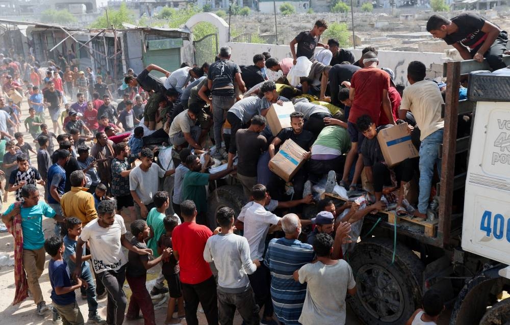 Palestinians collect aid supplies from a truck that entered Gaza, amid a ceasefire between Israel and Hamas, in Khan Younis, in the southern Gaza Strip, on Saturday. REUTERS