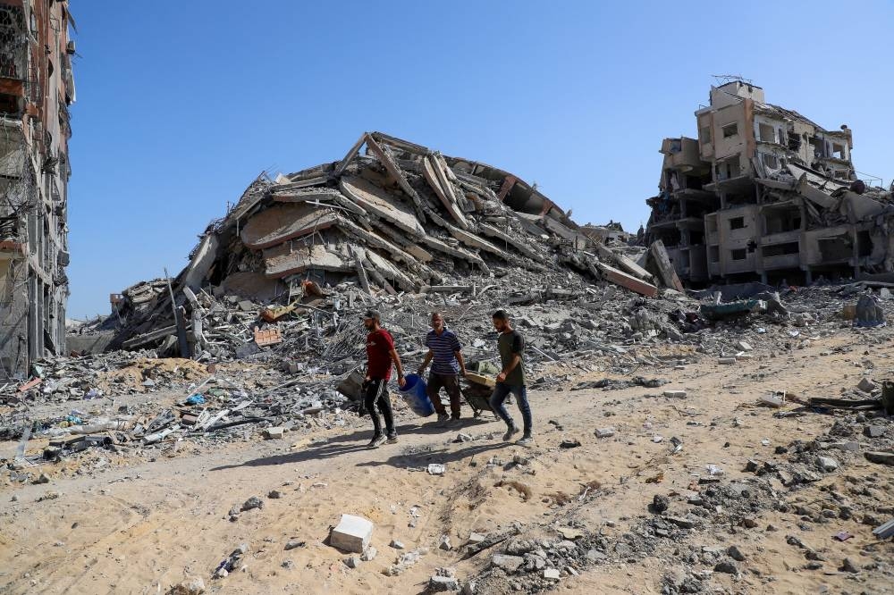 Palestinians walk near rubble following Israeli forces' withdrawal from the area, amid a ceasefire between Israel and Hamas in Gaza, in Gaza City, on Saturday. REUTERS