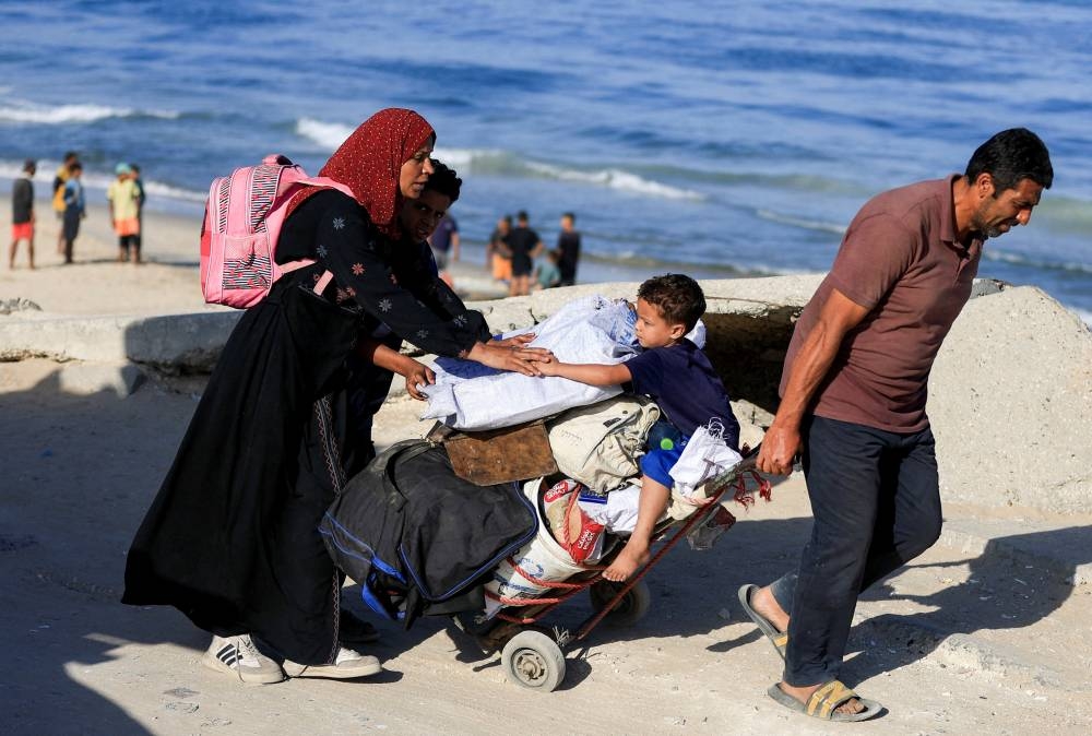 Palestinians, who were displaced to the southern part of Gaza at Israel's order during the war, make their way along a road as they return to the north, amid a ceasefire between Israel and Hamas in Gaza, in the central Gaza Strip, on Saturday. REUTERS