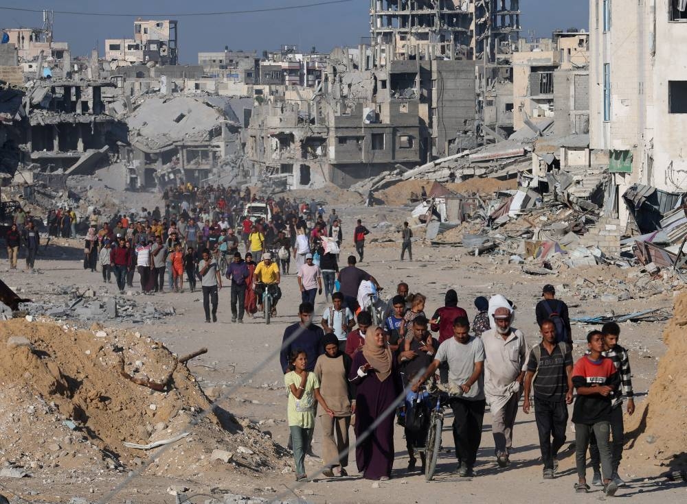 Palestinians walk past rubble as they return to their neighborhood, following Israeli forces' withdrawal from the area, amid a ceasefire between Israel and Hamas in Gaza, in Khan Younis, in the southern Gaza Strip, on Saturday. REUTERS