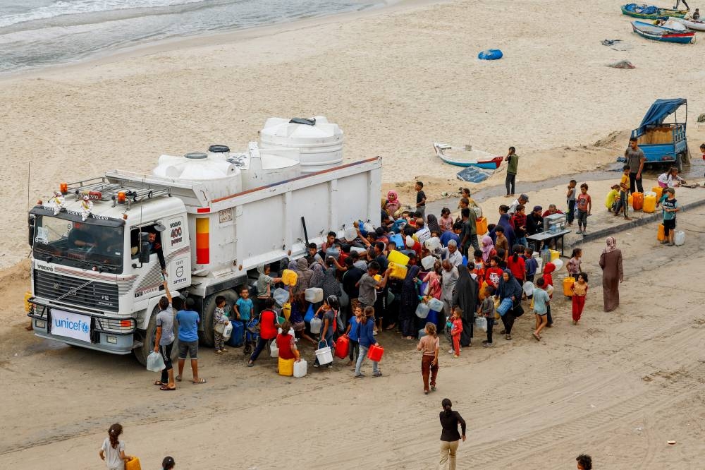 Displaced Palestinians fill containers with water amid a ceasefire between Israel and Hamas, in the central Gaza Strip, on Sunday. REUTERS