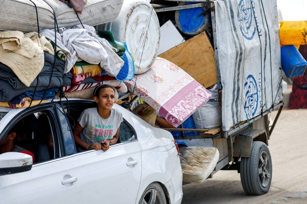 A Palestinian girl looks out from a window of a car carrying belongings, as she and other Palestinians who were displaced to the southern part of Gaza at Israel's order during the war make their way along a road, as they return to the north, amid a ceasefire between Israel and Hamas in Gaza, in the central Gaza Strip, on Sunday. REUTERS