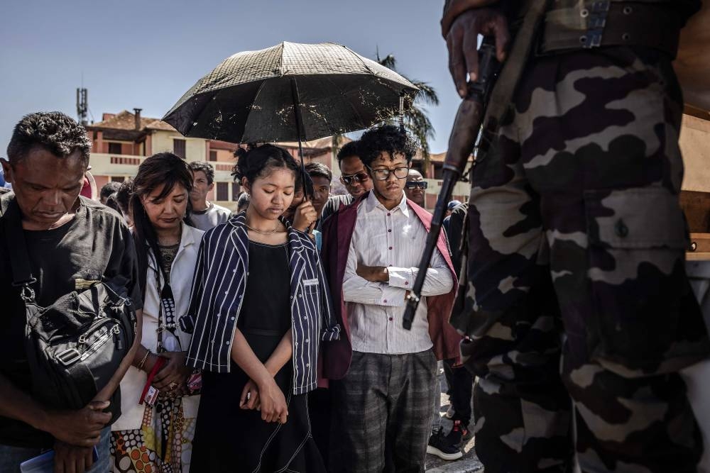 Residents bow their heads as they observe a minute of silence during a ceremony honouring protesters killed in anti-government demonstrations in Antananarivo, on Sunday. AFP