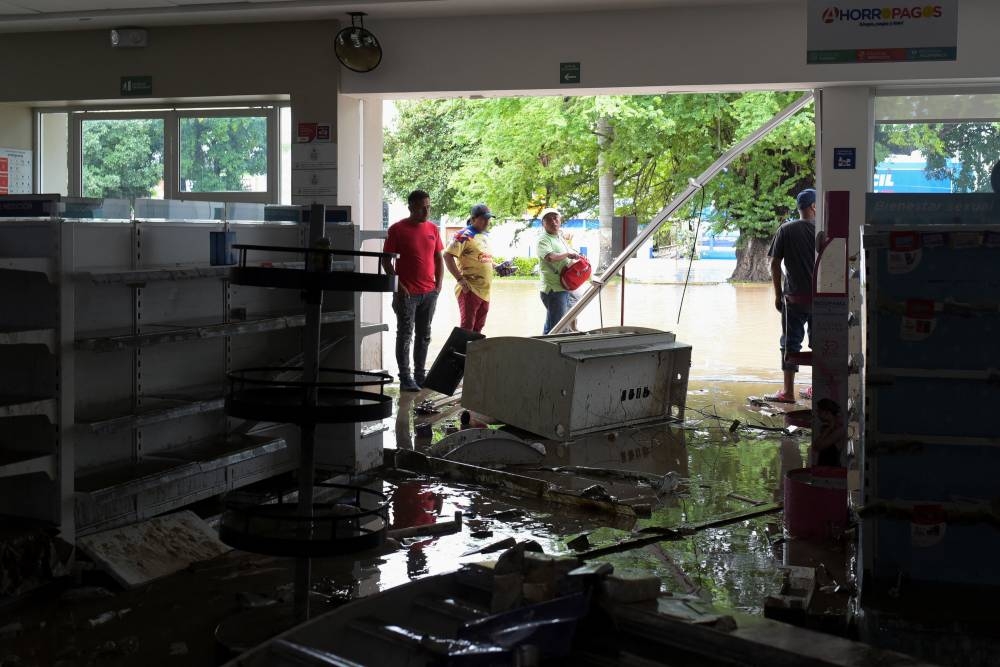 Men look inside a pharmacy affected by the rains after torrential rains that caused an overflow of rivers in Poza Rica, Veracruz state, Mexico, on Sunday. REUTERS