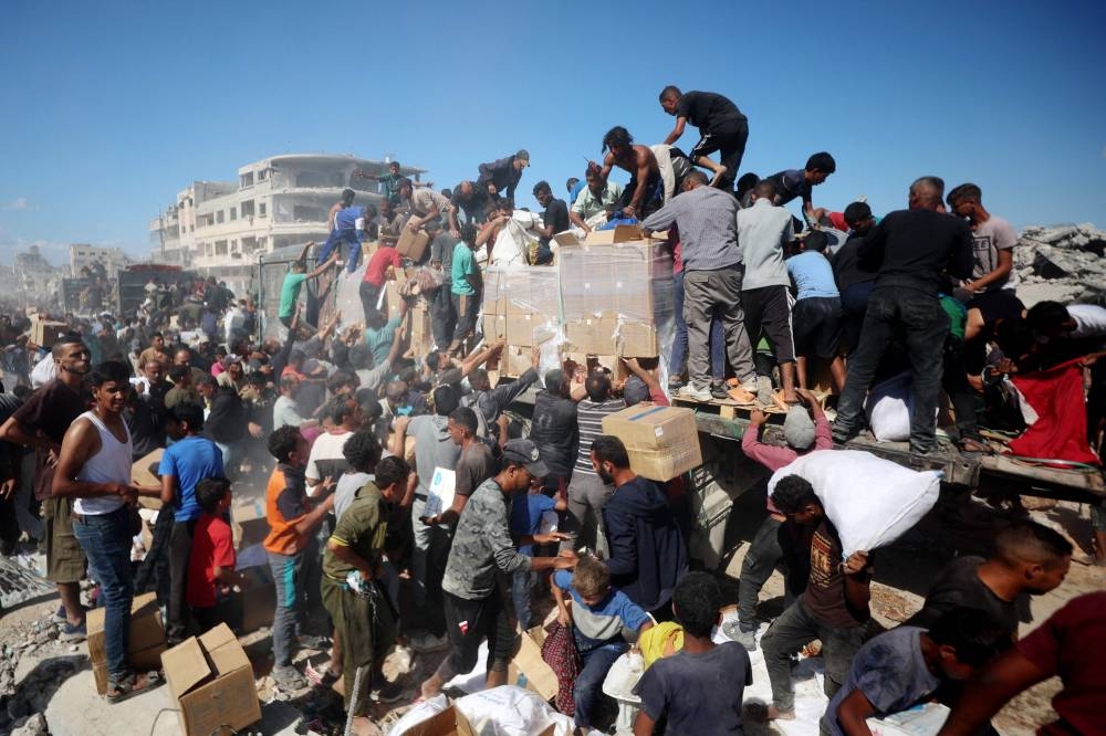 Palestinians collect aid parcels from aid trucks in Khan Yunis in the southern Gaza Strip Sunday