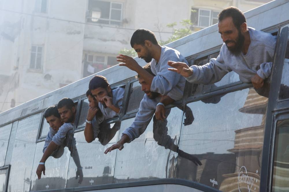 Freed Palestinian prisoners look out of a bus after they were released by Israel as part of a hostages-prisoners swap and a ceasefire deal between Hamas and Israel, in Khan Younis in the southern Gaza Strip, October 13, 2025. REUTERS