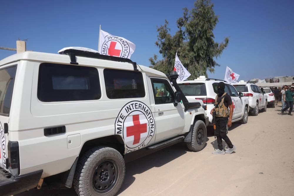 A Qassam Brigades militant stands next to vehicles of the International Committee of the Red Cross (ICRC) as they prepare to take off with the second batch of released Israeli hostages released by Hamas in the south of Deir el-Balah in the central Gaza Strip on Monday. AFP