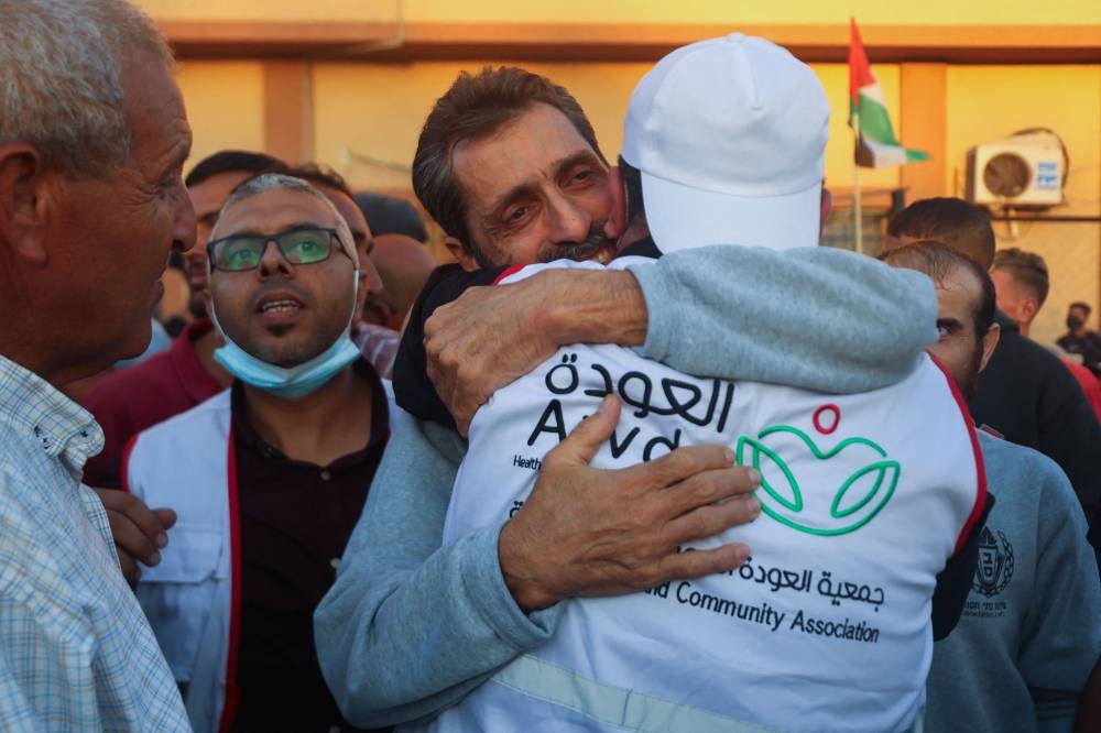 Palestinian hospital staff and well-wishers welcome the director of northern Gaza's Al-Awda Hospital Dr. Ahmad Mhanna, who was detained by Israeli forces from the hospital on December 18, 2023, following his release and arrival at the Nasser hospital in Khan Yunis in the southern Gaza Strip on Monday. AFP