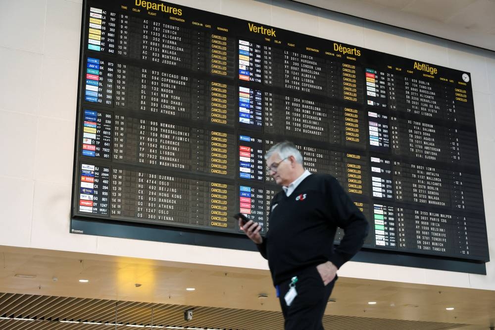An airport employee walks past a board displaying information on cancelled flights, during a nationwide strike against the government's reform plans, at Brussels Airport in Zaventem near Brussels, Belgium October 14, 2025.  REUTERS