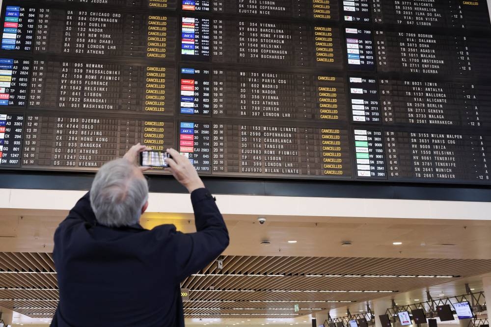 A passenger takes a photo of a board displaying information on cancelled flights, during a nationwide strike against the government's reform plans, at Brussels Airport in Zaventem near Brussels, Belgium October 14, 2025.  REUTERS