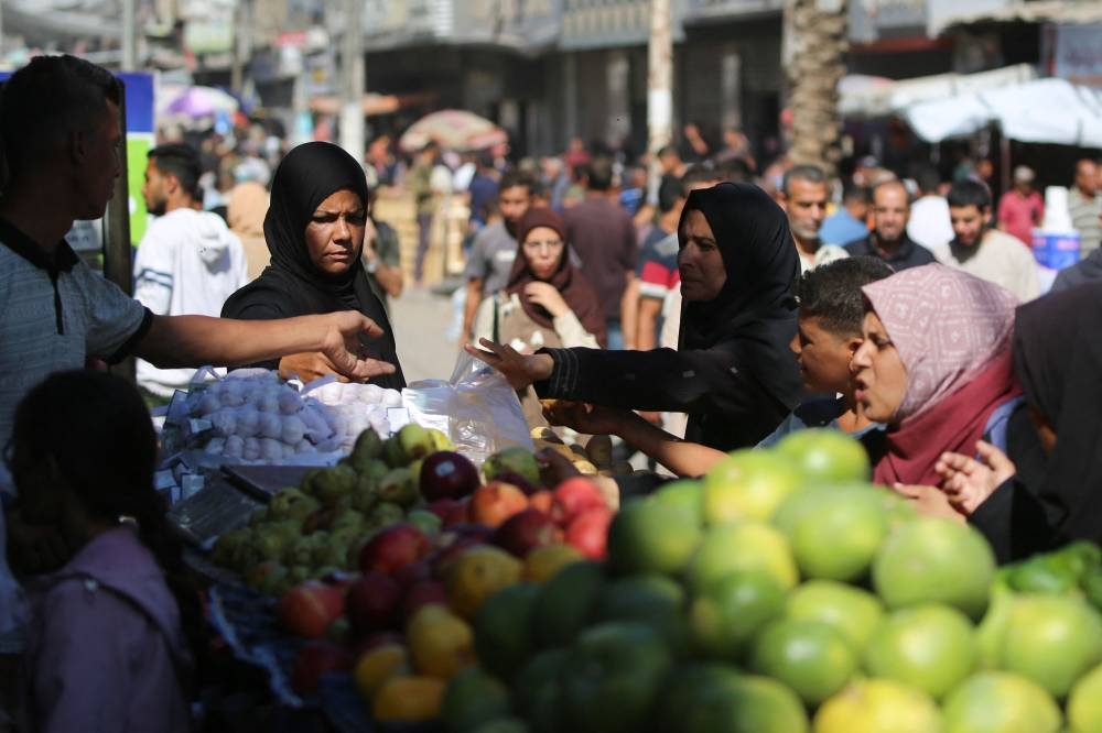 Palestinians shop for fruits and vegetables at a makeshift market in the Nuseirat refugee camp, located in the central Gaza Strip on Wednesday. AFP