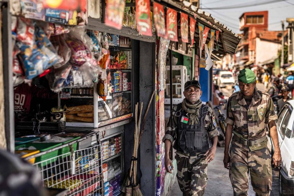 Members of Madagascar’s Army CAPSAT unit walk past a a commercial area near the CAPSAT base, a day after the unit announced it would assume power in Antananarivo on Wednesday. AFP