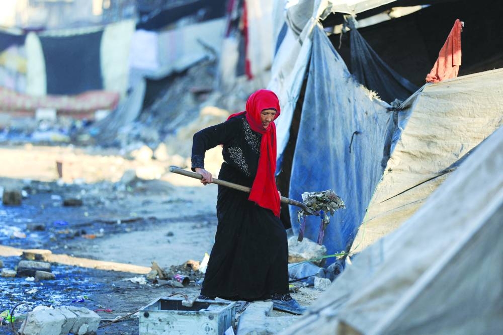 A Palestinian woman cleans an area next to tents, amid a ceasefire between Israel and Hamas, in Gaza City.