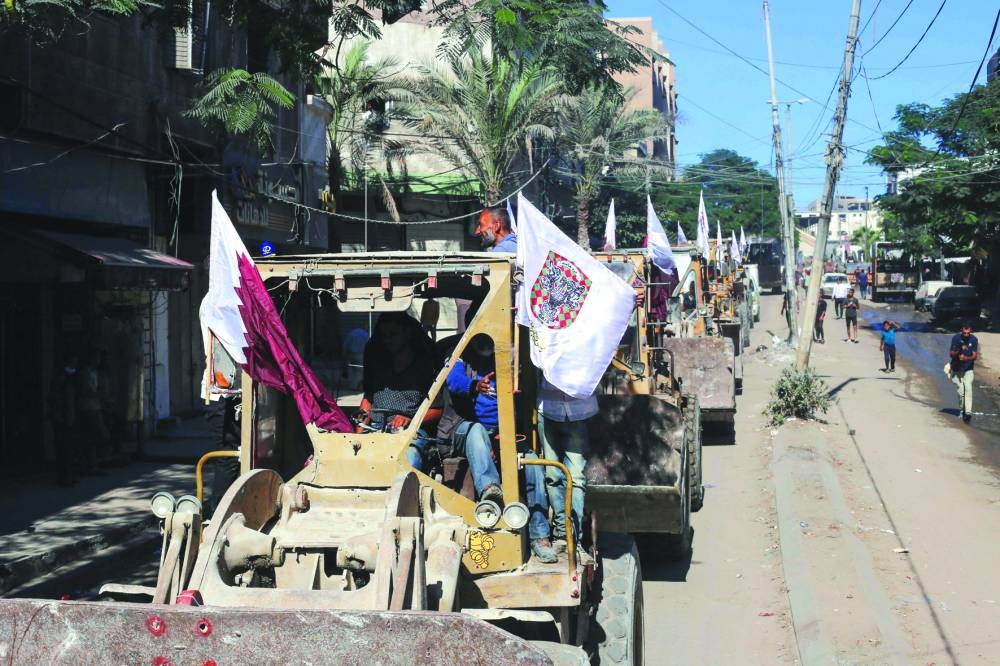 Bulldozers deployed by the Gaza Municipality drive past Palestinians on the way to clear building rubble from main axes and streets in Gaza City, amid a ceasefire between Israel and Palestinian factions, on Tuesday. AFP