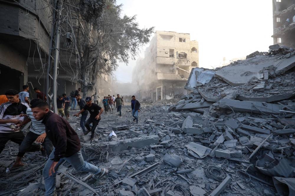 People run for cover following an Israeli strike that targeted a building in the Bureij camp in the central Gaza Strip Sunday.