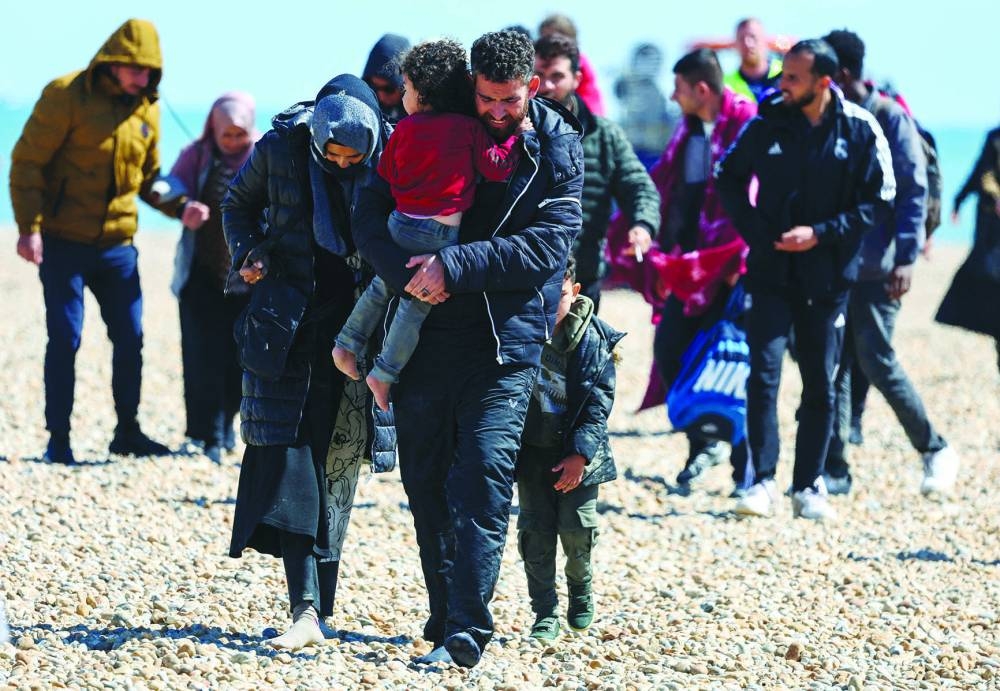 File photo: People, believed to be migrants, walk in Dungeness, Britain.