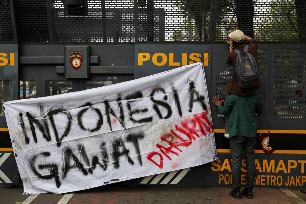 University students place a banner which reads "Indonesia in emergency" on a police barricade during a protest on the first anniversary of President Prabowo's administration, criticizing government policies, including the free meals programme, in Jakarta, on Monday. REUTERS