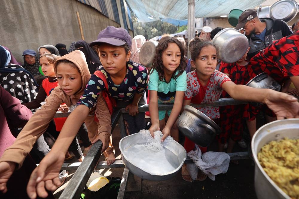 Palestinian children gather to receive food portions from a charity kitchen in the Nuseirat refugee camp, located in the central Gaza Strip, on Tuesday. AFP