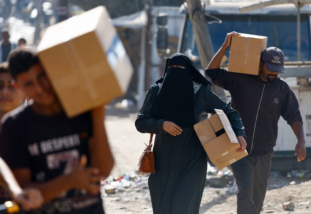 Palestinians carry aid supplies that entered Gaza, amid a ceasefire between Israel and Hamas in Gaza, in Zawaida, in the central Gaza Strip, on Tuesday. REUTERS