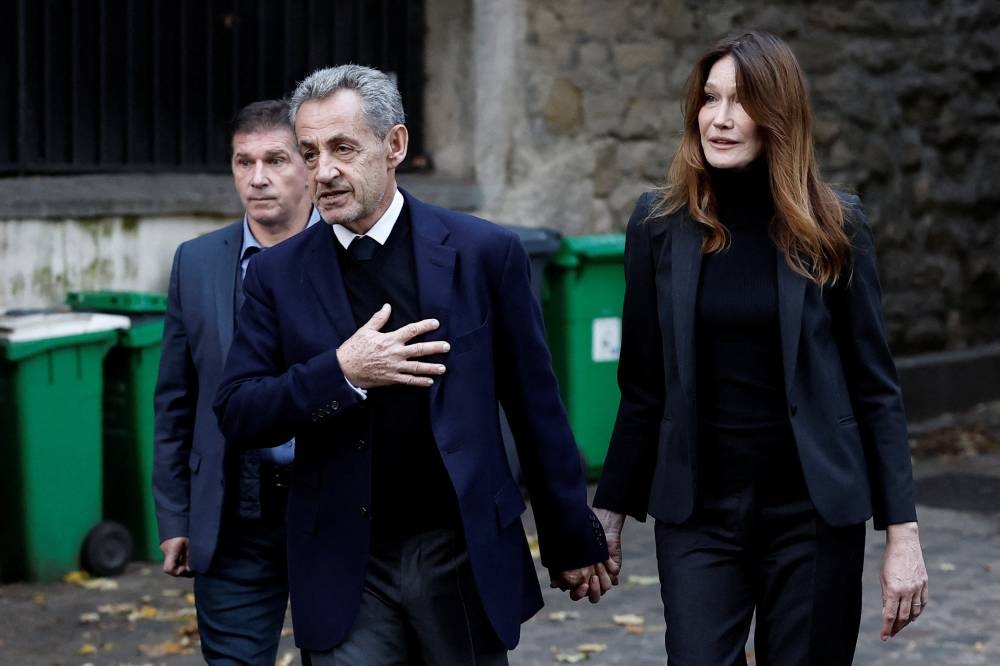 Former French President Nicolas Sarkozy leaves his house with his wife Carla Bruni-Sarkozy on the day of his incarceration at the Sante prison to begin his five-year prison sentence, in Paris on Tuesday. REUTERS