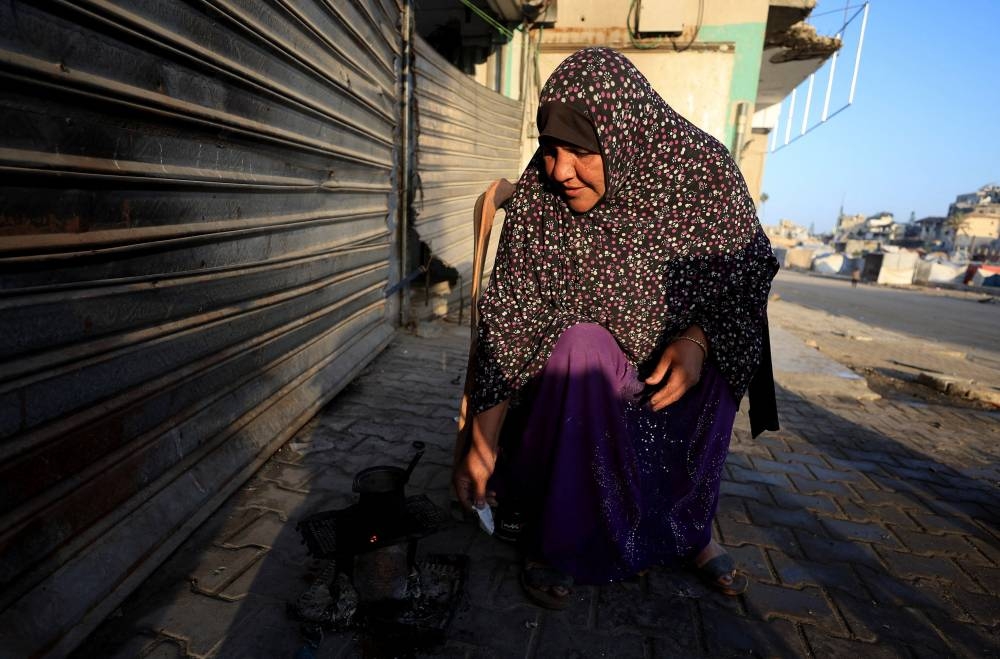 A Palestinian woman heats water along a street, amid a ceasefire between Israel and Hamas, in Gaza City, on Monday. REUTERS