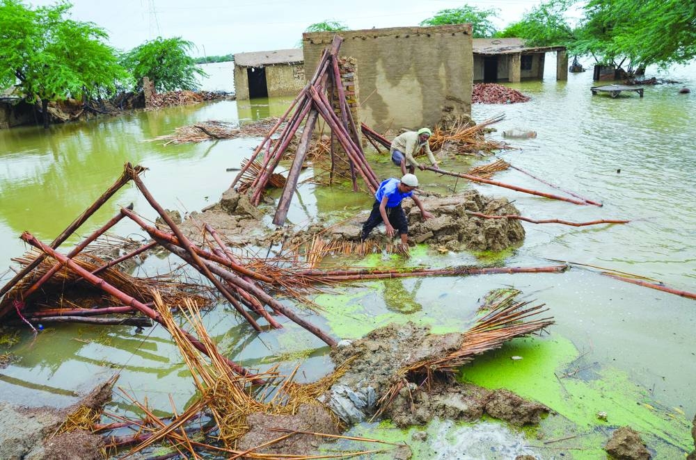 
People retrieve bamboos from a damaged house following rains and floods during the monsoon season in Dera Allah Yar, district Jafferabad, Balochistan, Pakistan. (Reuters/File photo) 