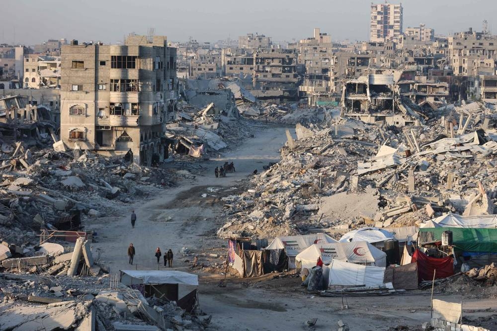 Palestinians walk past the rubble of destroyed buildings in the Sheikh Radwan neighborhood of Gaza City on Wednesday. AFP