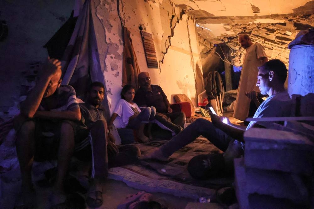 Palestinians take shelter in a damaged building in Khan Yunis, in the Gaza Strip Saturday.
