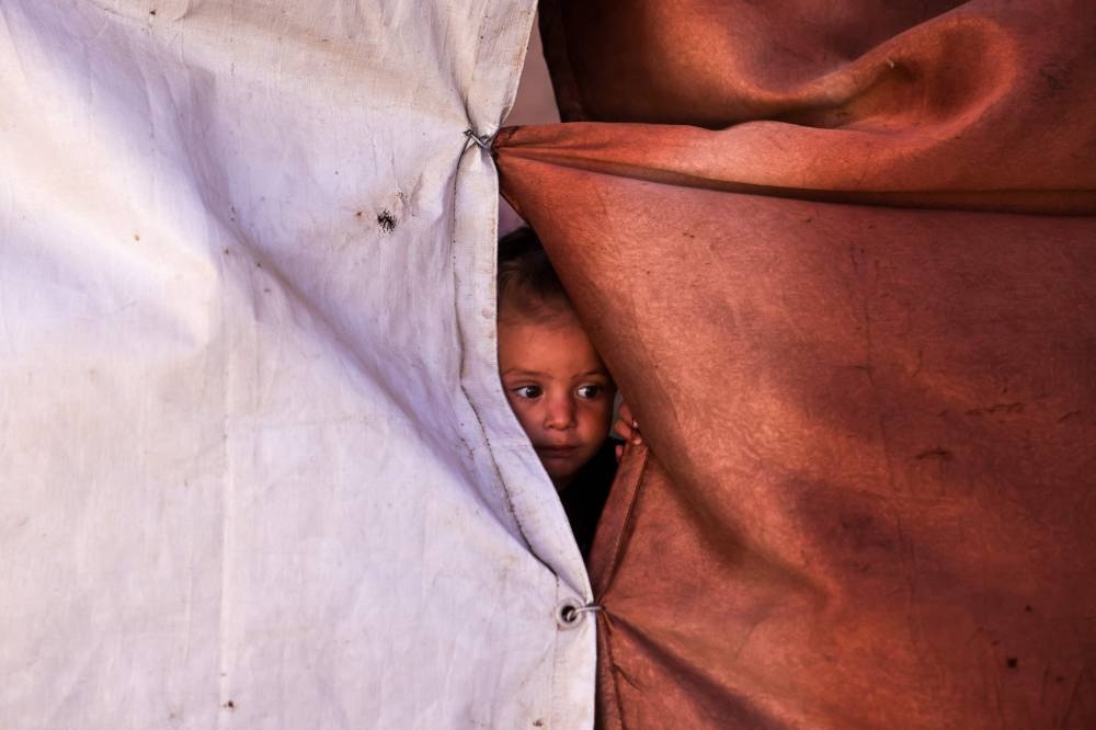 A child looks through an opening of a makeshift shelter in Khan Younis, in the southern Gaza Strip Saturday.