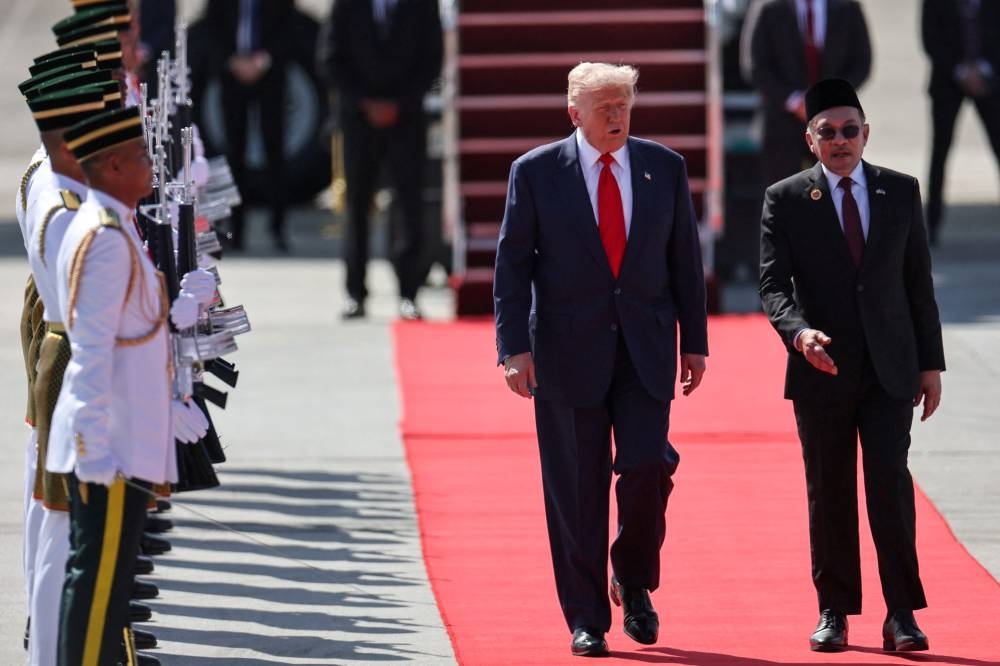 US President Donald Trump (C) speaks with Malaysia's Prime Minister Anwar Ibrahim (R) as he walks from Air Force One upon arrival at Kuala Lumpur International Airport in Kuala Lumpur on October 26, 2025. US President Donald Trump arrived in Malaysia on October 26 on the first leg of an Asian tour that will include high-stakes trade talks with Chinese counterpart Xi Jinping. (AFP)