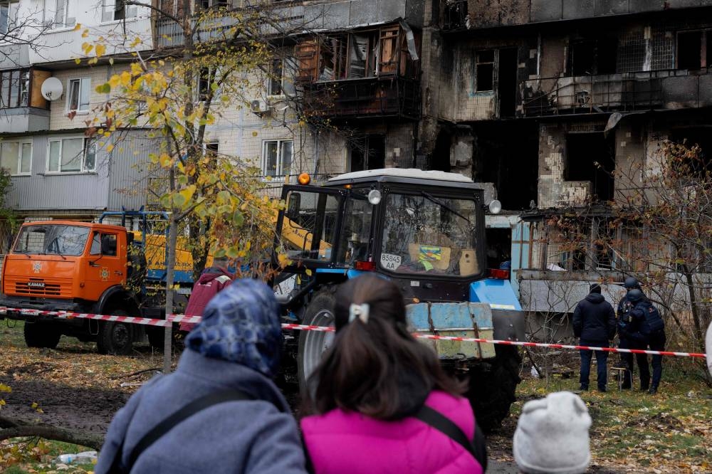 Local residents look at a damaged residential building following a drone attack in Kyiv, on October 26, 2025, amid the Russian invasion of Ukraine. (AFP)