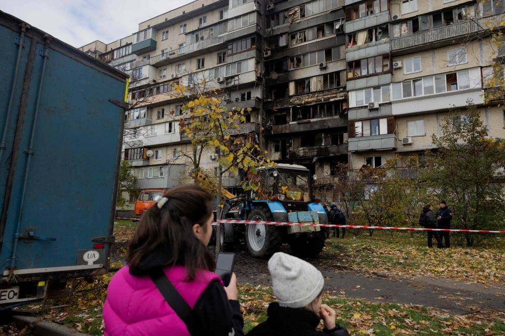 Local residents look at a damaged residential building following a drone attack in Kyiv, on October 26, 2025, amid the Russian invasion of Ukraine. (AFP)