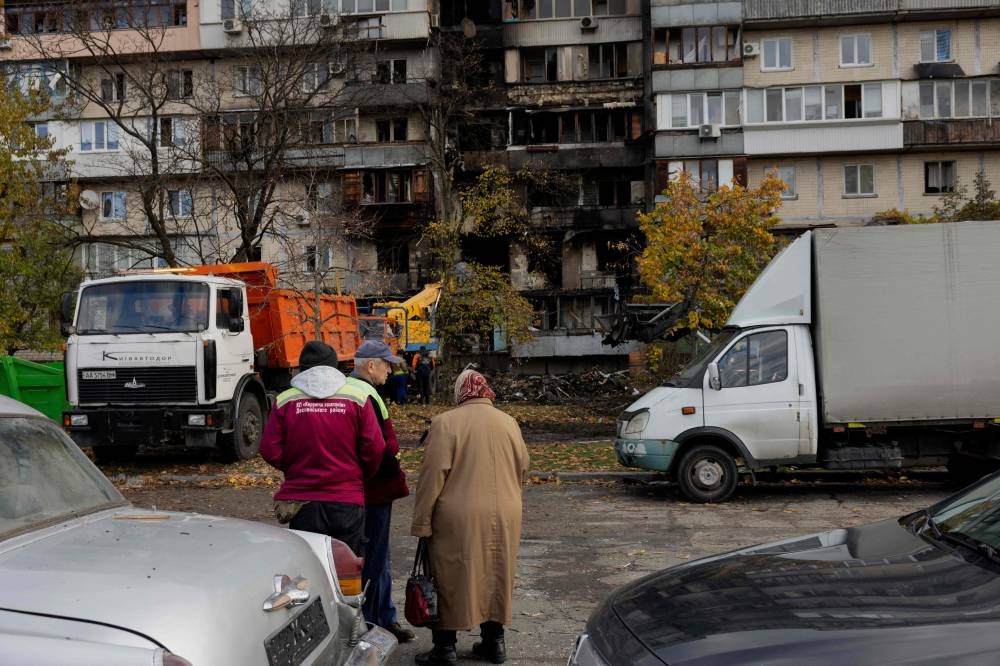 Local residents look at a damaged residential building following a drone attack in Kyiv, on October 26, 2025, amid the Russian invasion of Ukraine. (AFP)