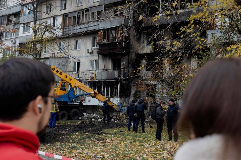 Local residents look at a damaged residential building following a drone attack in Kyiv, on October 26, 2025, amid the Russian invasion of Ukraine. (AFP)
