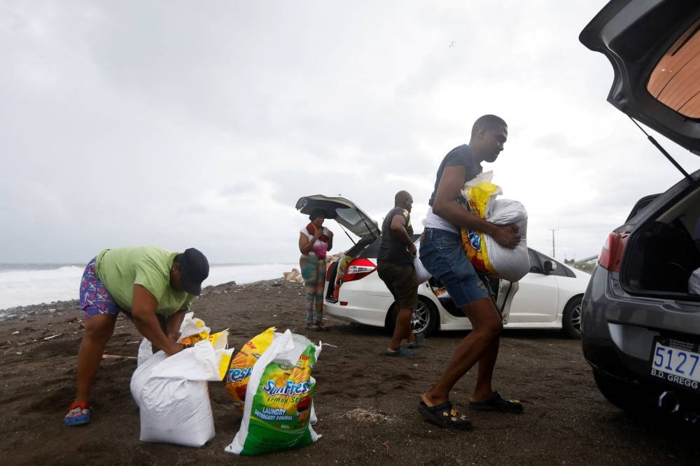 People carry bags with sand to load them into cars, in preparation for the arrival of Hurricane Melissa, in Port Royal, Jamaica, on Sunday.  REUTERS