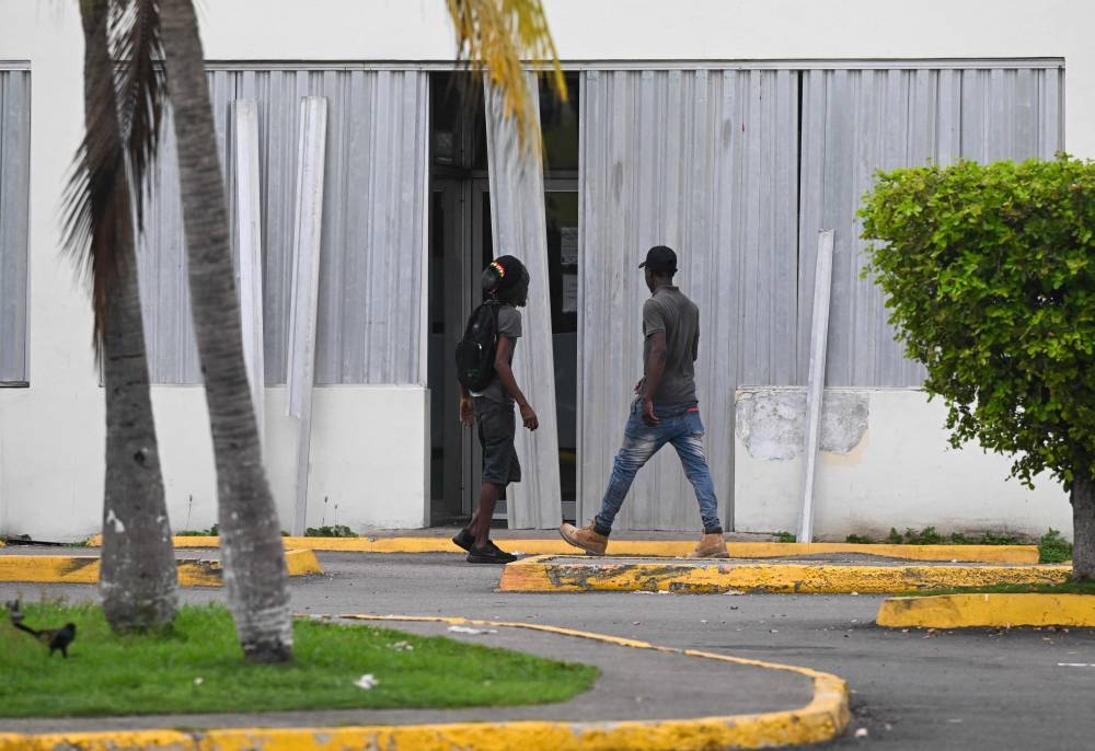 Men install storm shutters at a business in preparation for the arrival of Hurricane Melissa in Portmore, St. Catherine parish, Jamaica, on Sunday.  AFP