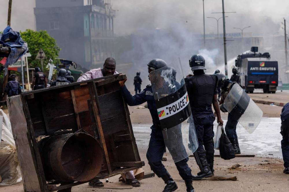 An anti-riot police officer removes a barricade during clashes with supporters of Cameroon presidential candidate Issa Tchiroma, after the Constitutional Council declared President Paul Biya the winner of the October 12 presidential election, in Douala, Cameroon, on Monday. REUTERS