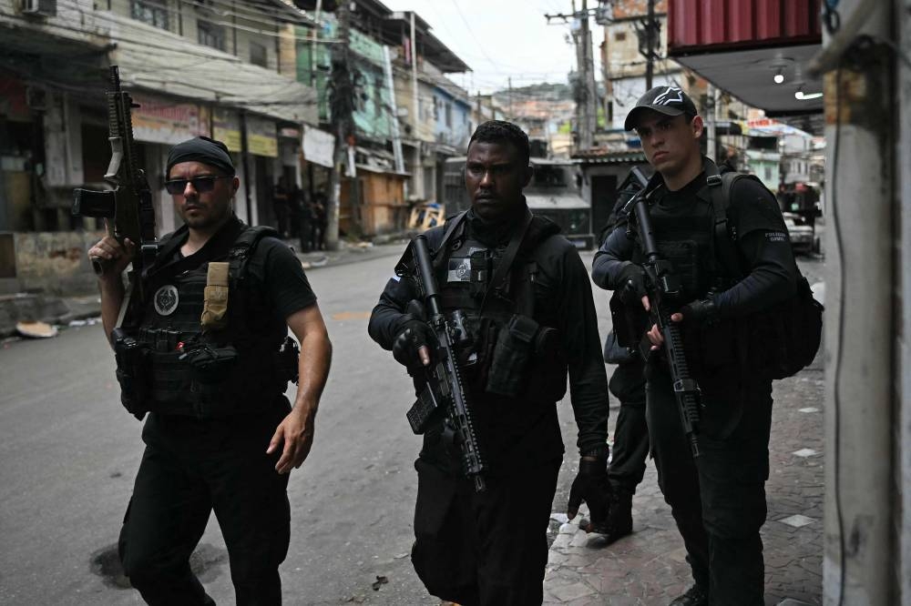 Police officers taking part in the Operacao Contencao (Operation Containment) walk their way out of t the Vila Cruzeiro favela, in the Penha complex, in Rio de Janeiro, Brazil, on Tuesday. AFP