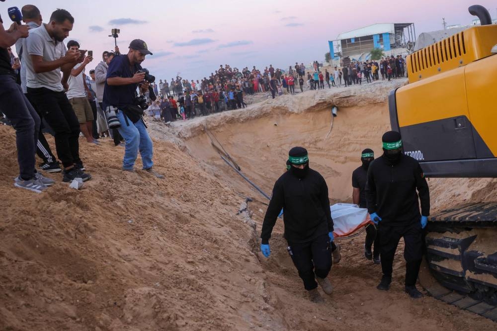 People look on as Hamas fighters carry a body retrieved from a tunnel in an area north of Khan Yunis in the southern Gaza Strip on Tuesday. AFP