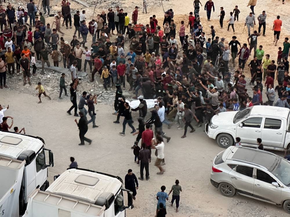 People look on as Hamas fighters carry a body retrieved from a tunnel in an area north of Khan Yunis in the southern Gaza Strip on Tuesday. AFP