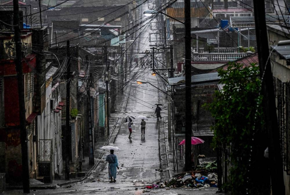 People walk in a street before Hurricane Melissa hits the city of Santiago de Cuba, Cuba on October 28, 2025. (AFP)