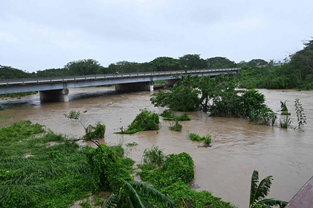 The Rio Cobre comes out of its banks near St. Catherine, Jamaica, on October 28, 2025. Ferocious winds and torrential rain tore into Jamaica Tuesday as Hurricane Melissa made landfall, the worst storm ever to strike the island nation and one of the most powerful hurricanes on record. The extremely violent Category 5 system was still crawling across the Caribbean, promising catastrophic floods and life-threatening conditions as maximum sustained winds reached a staggering 185 miles per hour (295 kilometers per hour). (AFP)