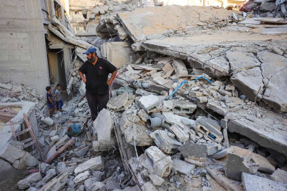 A man and children look at the rubble of a house destroyed in an Israeli strike in Khan Yunis, in the southern Gaza Strip, on Wednesday. AFP