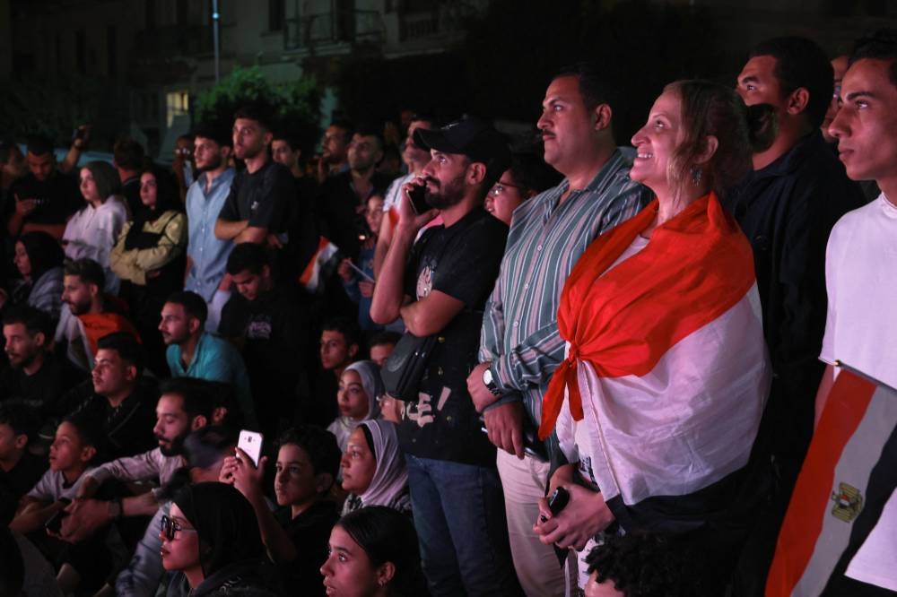 People watch the official opening ceremony of the Grand Egyptian Museum (GEM) on a big screen in the downtown area near Tahrir Square, in front of Abdeen Palace Museum, in Cairo on Saturday. REUTERS
