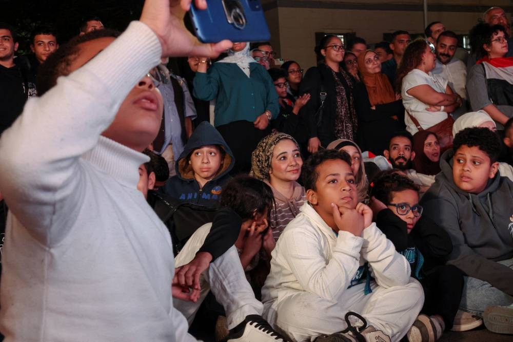 People gather to watch the official opening ceremony of the Grand Egyptian Museum (GEM) on a big screen in the downtown area near Tahrir Square, in front of Abdeen Palace Museum, in Cairo on Saturday. REUTERS