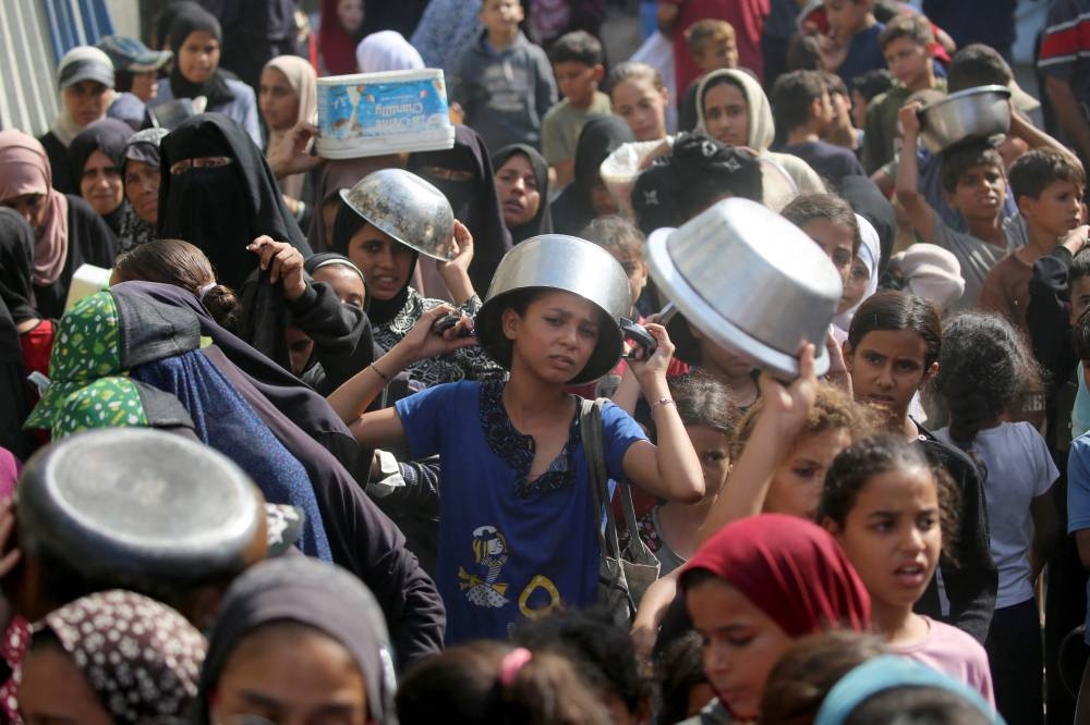 A young displayed Palestinian boy waits with his pot to receive a portion of food, at a shelter where families been living, in Nuseirat in the central of Gaza Strip on Sunday. AFP