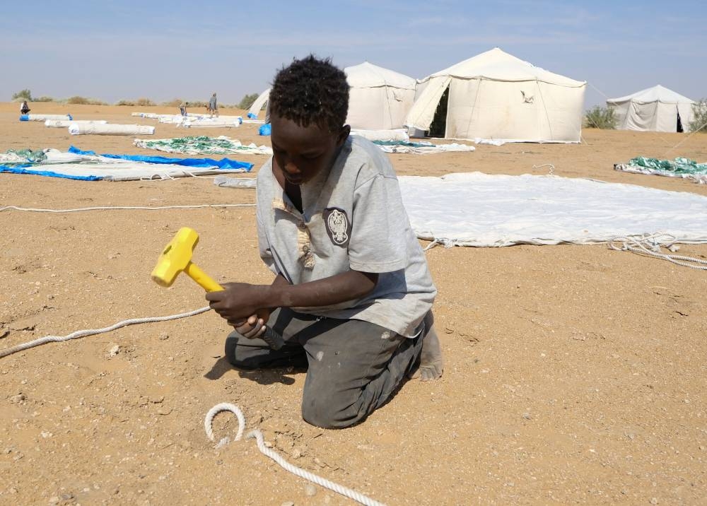 A displaced child sets up a tent in a camp in Al-Dabbah, Sudan, on Monday. REUTERS